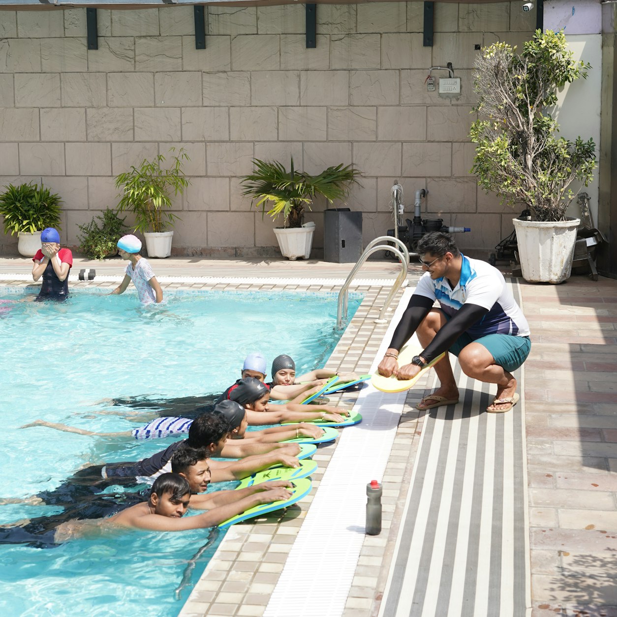 Professora orientando crianças com pranchas na piscina